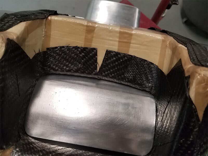 Close up image of portable X-ray machine in manufacture. There is metallic tool being used for layup. Prepreg is on the tool and surrounding a brown plastic coated structure.
